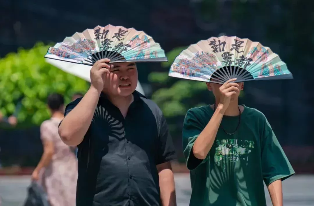 重慶,遊客用扇子遮陽。