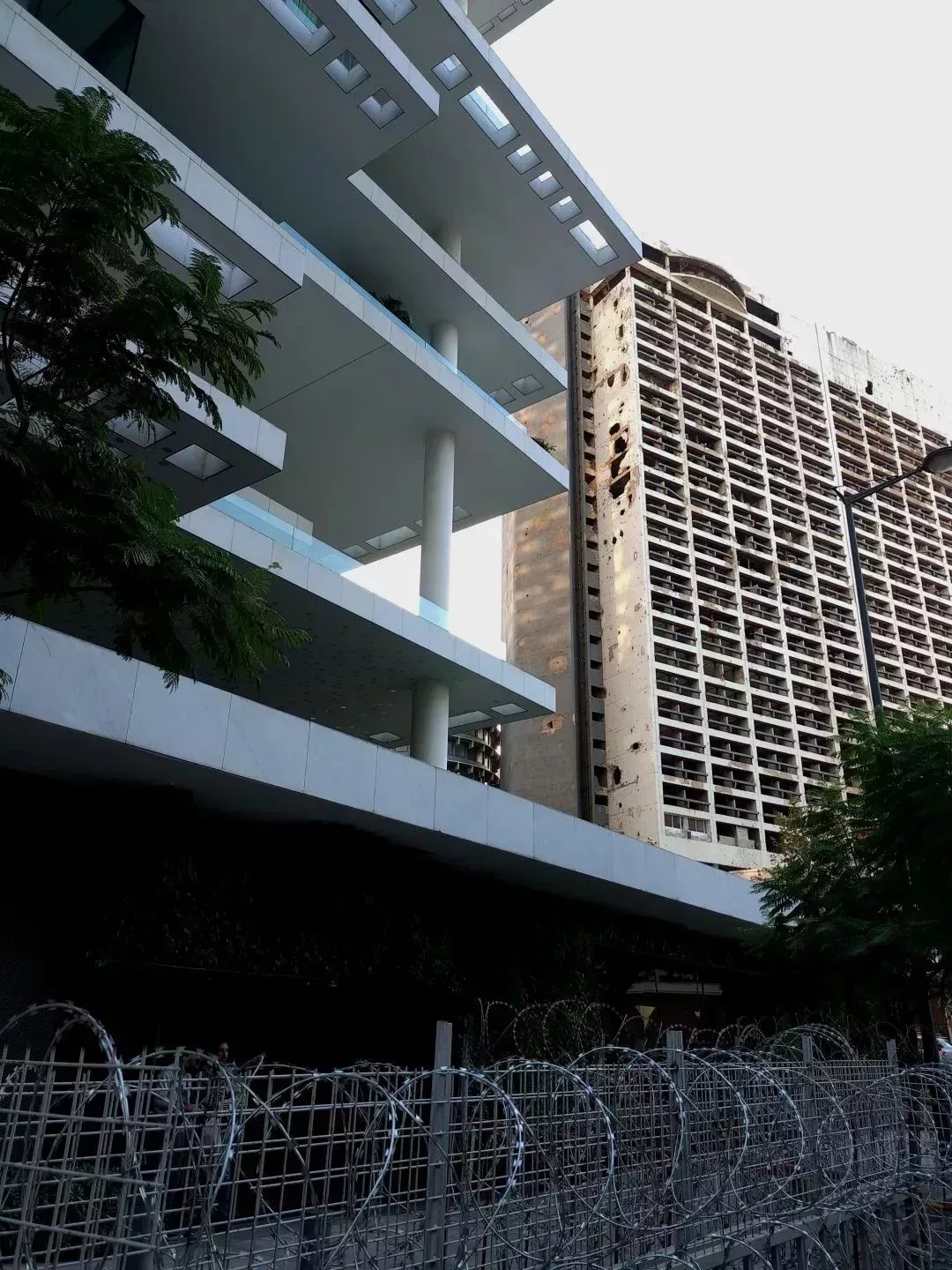 把一新一舊兩座建築塞進同一畫面:後面那座是被摧毀的假日酒店,前面這座是貝魯特目前最高檔的住宅小區“貝魯特露臺”。