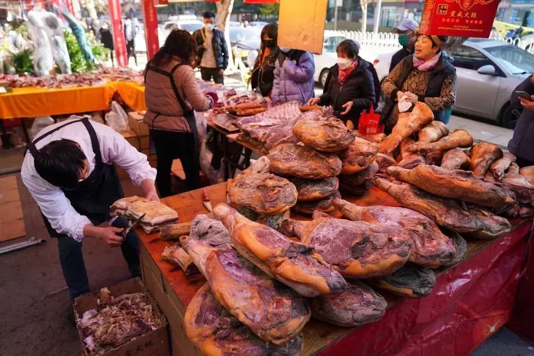 春節將近,準備年貨的人們在市場上採購火腿。